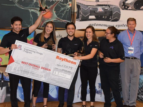 Five university students holding a large check with the presenter from Raytheon