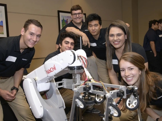 A senior design team stands with their robotics project