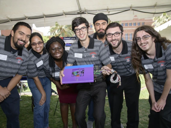 Four members of a senior design team with their closed loop controller circuit board