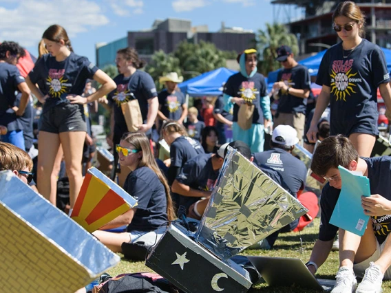 a group of students work outdoors on hand-built solar ovens