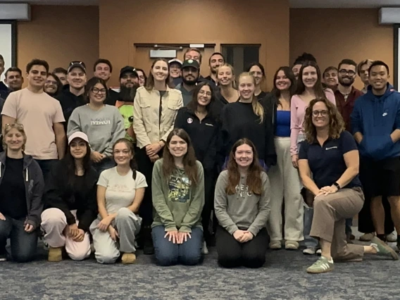 A group of students pose for a class photo with their mentor.