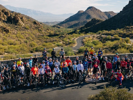 a group of cyclists standing in front of mountains