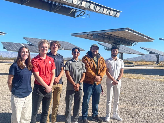 a group of students stands in front of several solar arrays