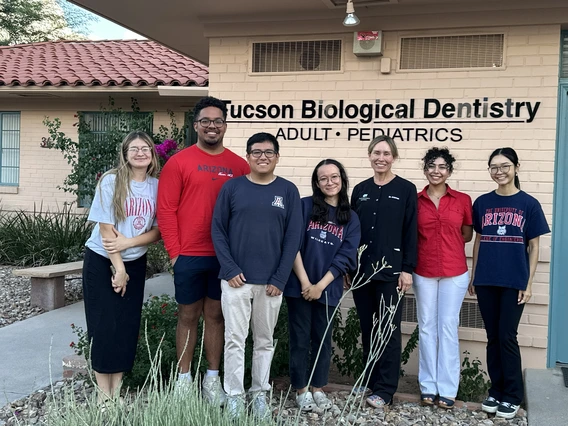 A group of students take a photo with a dentist.