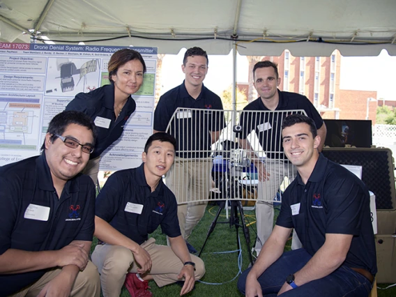 Five university student surrounding a design project under a tent