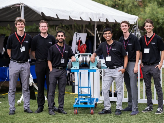 6 students pose with a battle robot