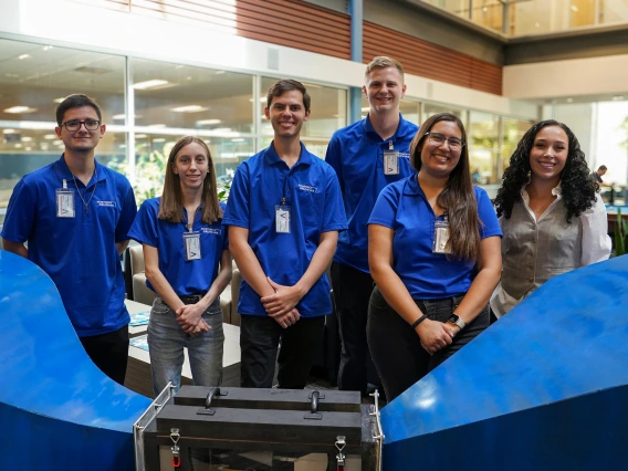 Six people pose behind a subscale wind tunnel