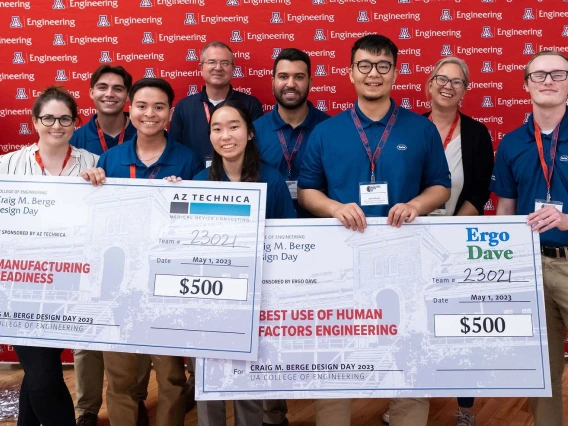 A group of students holds two oversized prize checks