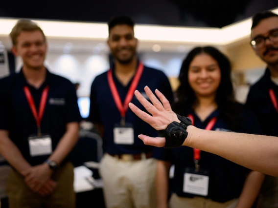 Someone models a wrist brace while students look on in the background