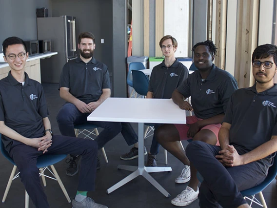 Students sit around table smiling