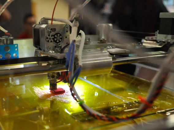 Close up image of a 3D printer making a red object