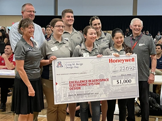 Eight people pose with a large prize check