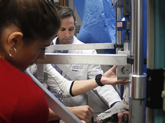 A man and a woman adjusting a replica of a skeletal foot inside a machine.