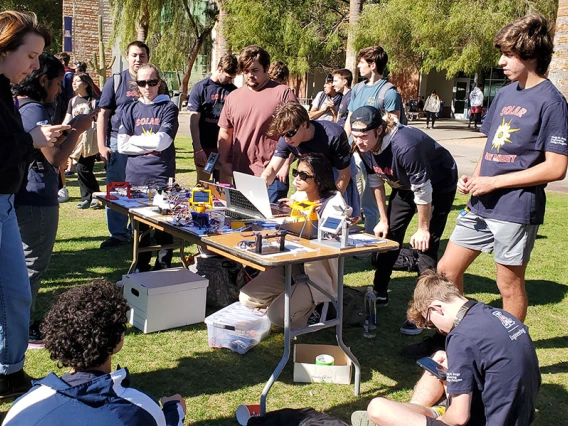 Students gather around a table holding solar trackers