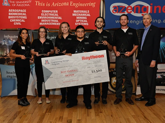 Presenting sponsor and three female and three male students holding triangle-shaped glass awards and a large award check 