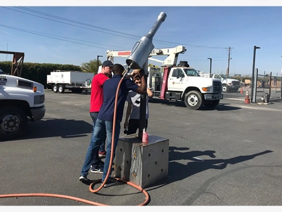 Three university students gathered around a metal contraption for extracting gas
