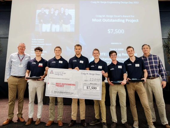 a group of students pose with a large check