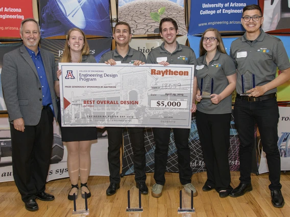 Man in suit with 5 students holding large award check