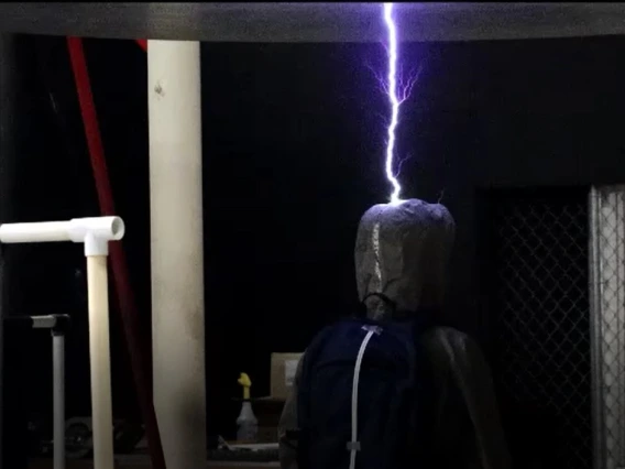 A mannequin in a dark room being struck by lightning