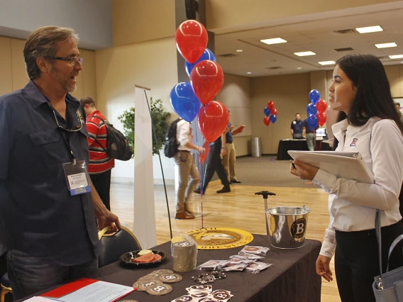 Image of Dennis Arnold talking to student at an open house