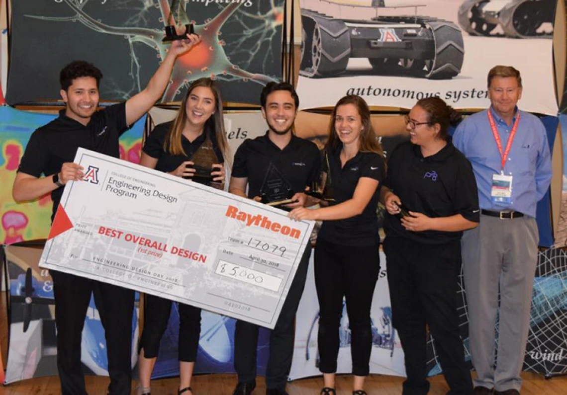 Five university students holding a large check with the presenter from Raytheon