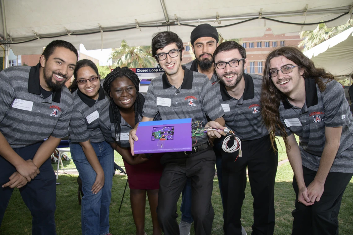 Four members of a senior design team with their closed loop controller circuit board