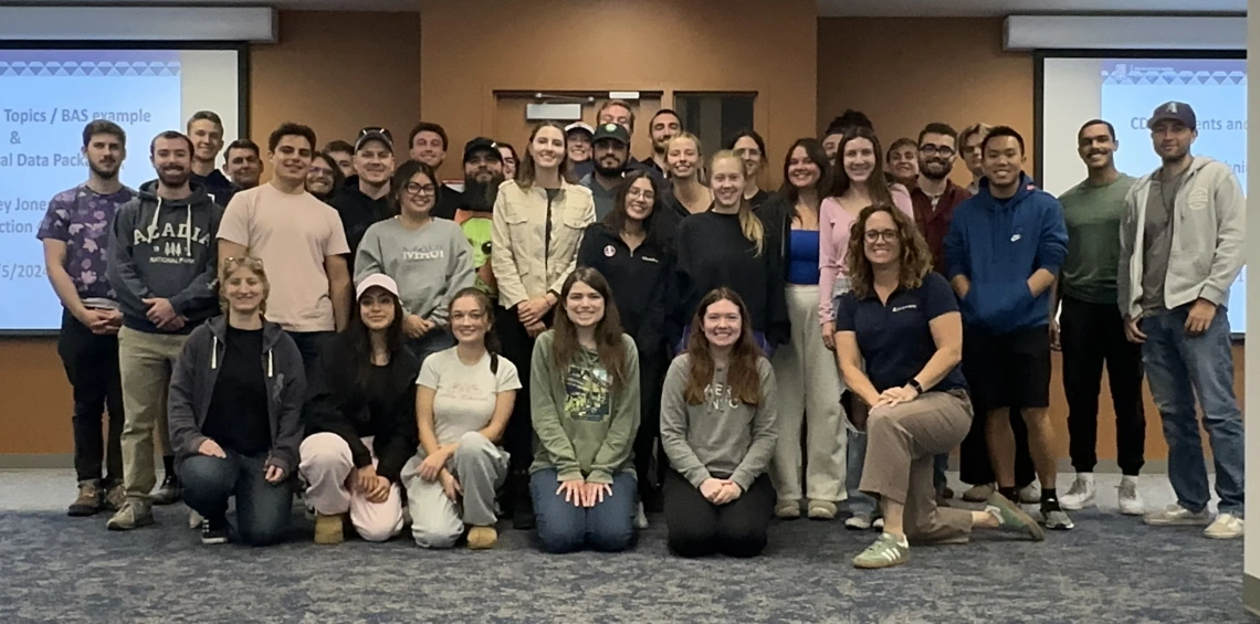 A group of students pose for a class photo with their mentor.