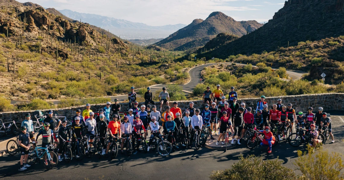 a group of cyclists standing in front of mountains