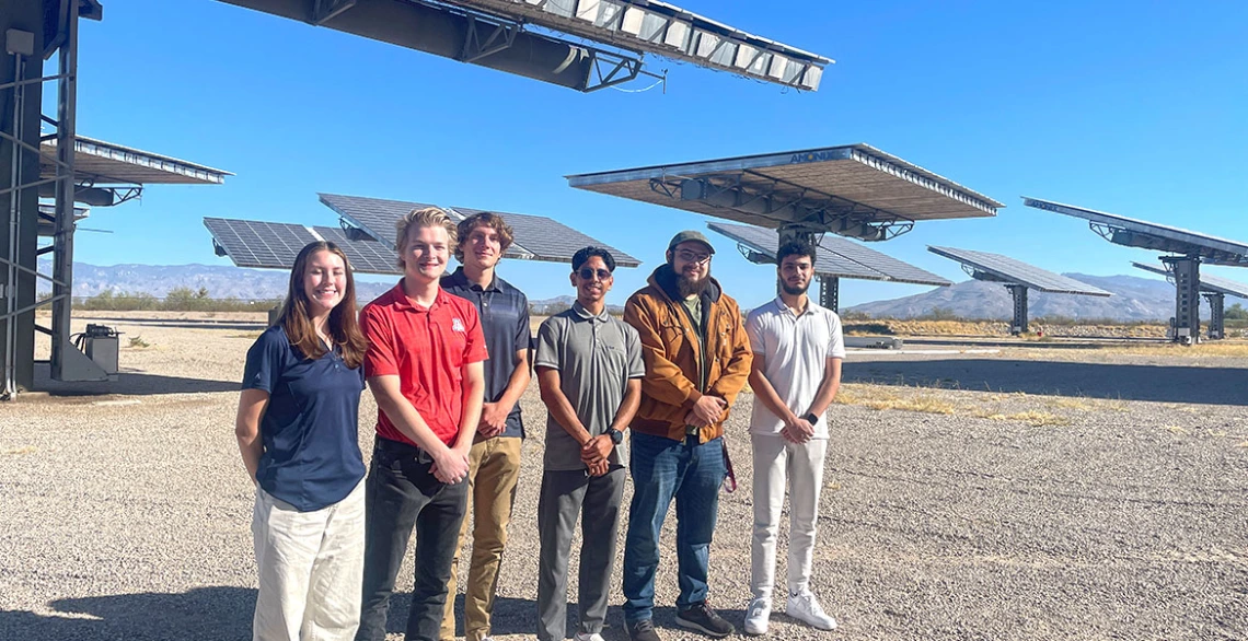 a group of students stands in front of several solar arrays