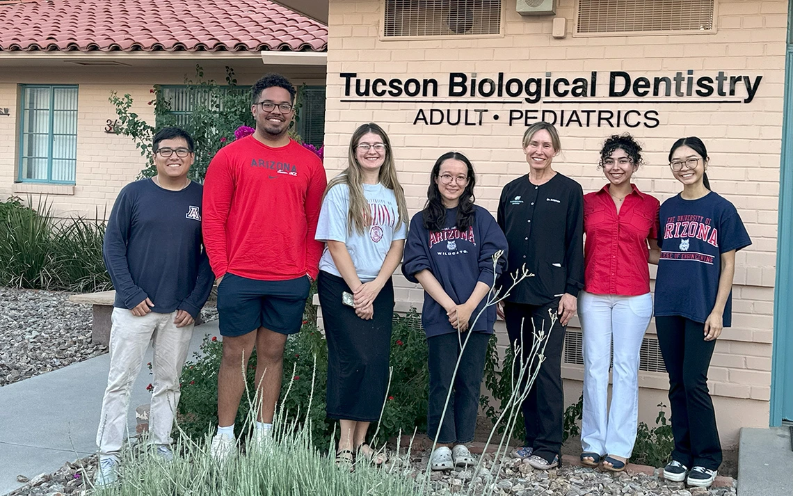 Six students pose for a photo outside a dentist's office with the dentist.