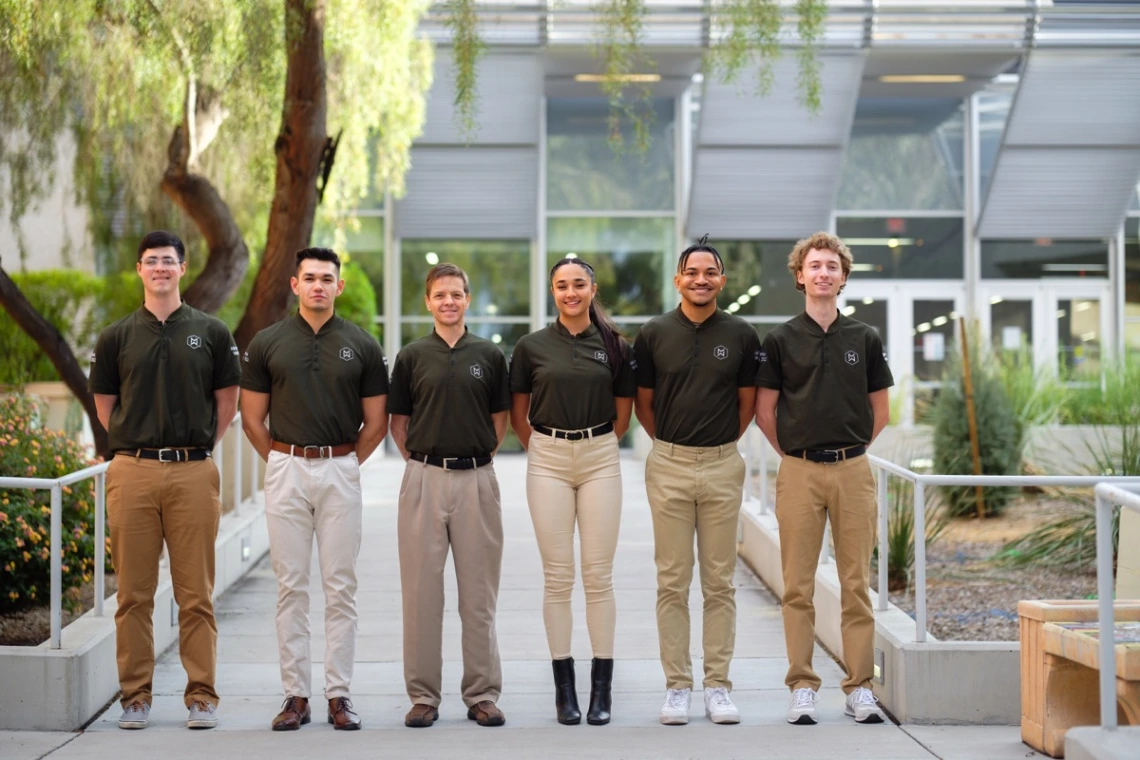 a group of six students poses outdoors