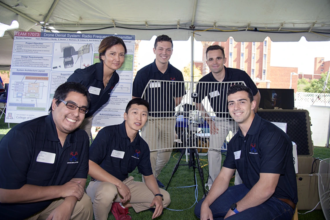 Five university student surrounding a design project under a tent