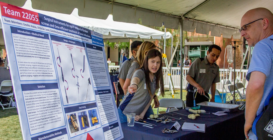 a group of students at an outdoor expo table