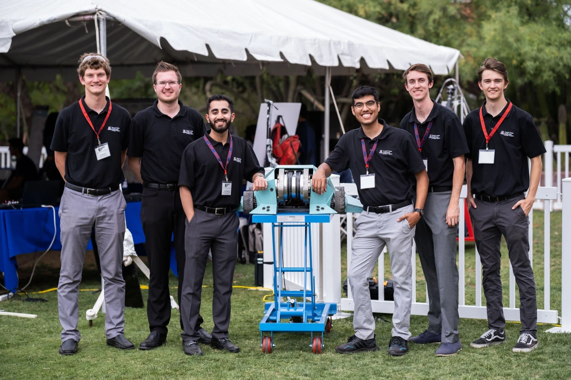 6 students pose with a battle robot