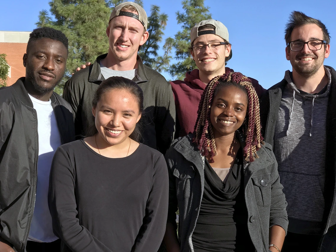 A group of six students, four men in the back row, two women in the front row, posing for a group shot