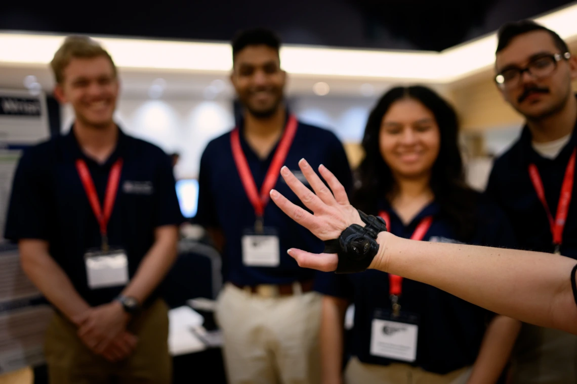 Someone models a wrist brace while students look on in the background