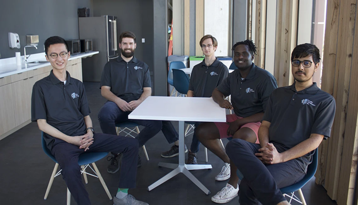 Students sit around table smiling