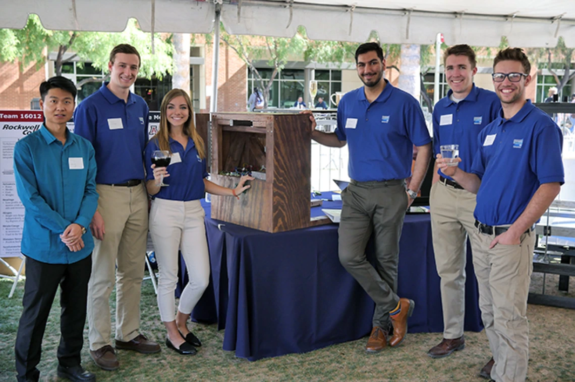 Team 16012 Six university students pose with their turbulence-compensated table mechanism outside under a tent