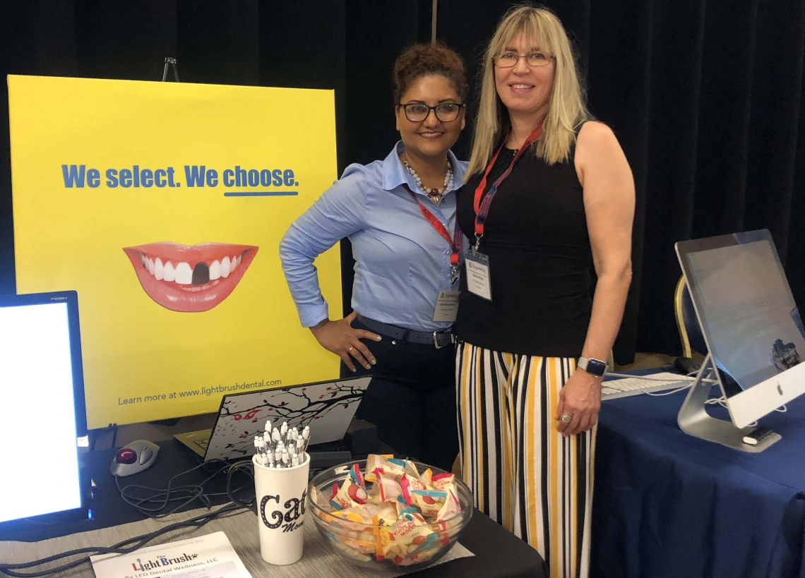 two people stand at a conference booth