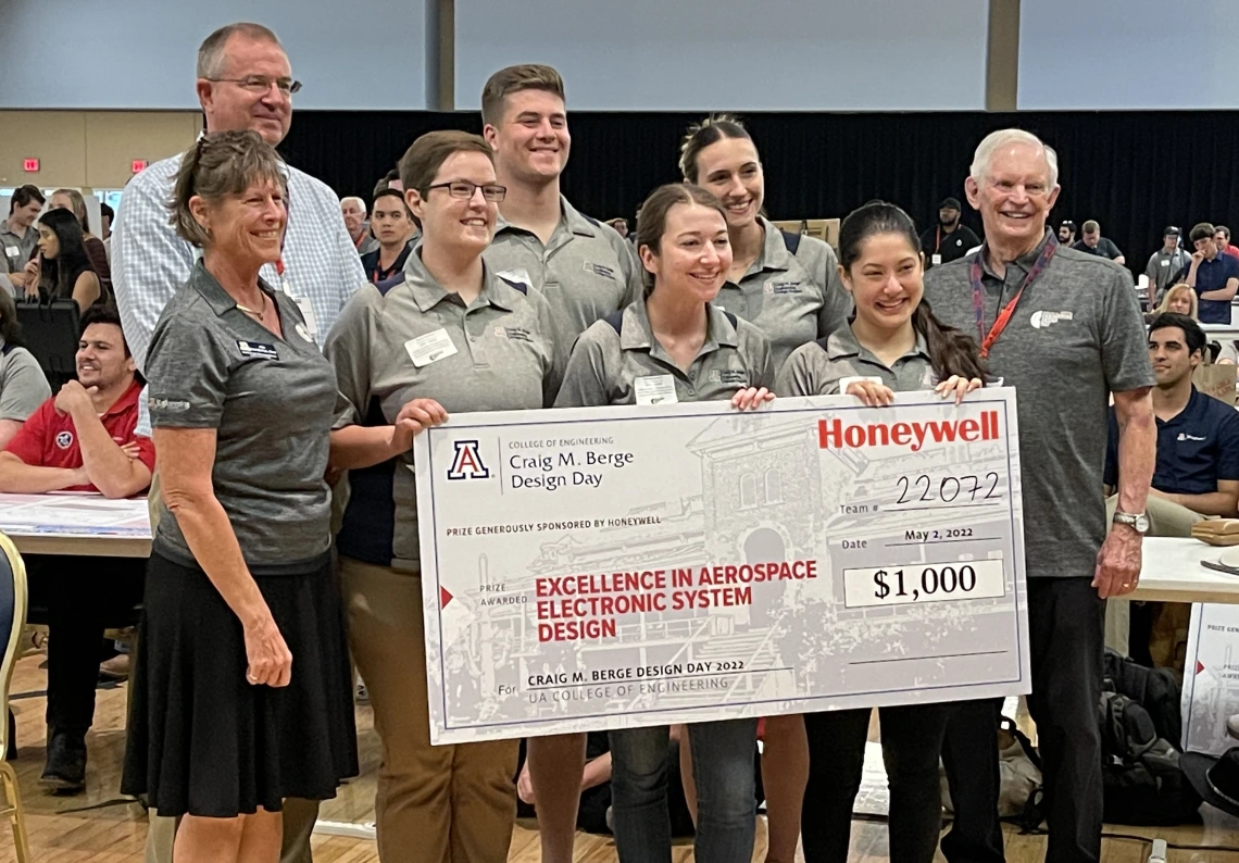 Eight people pose with a large prize check