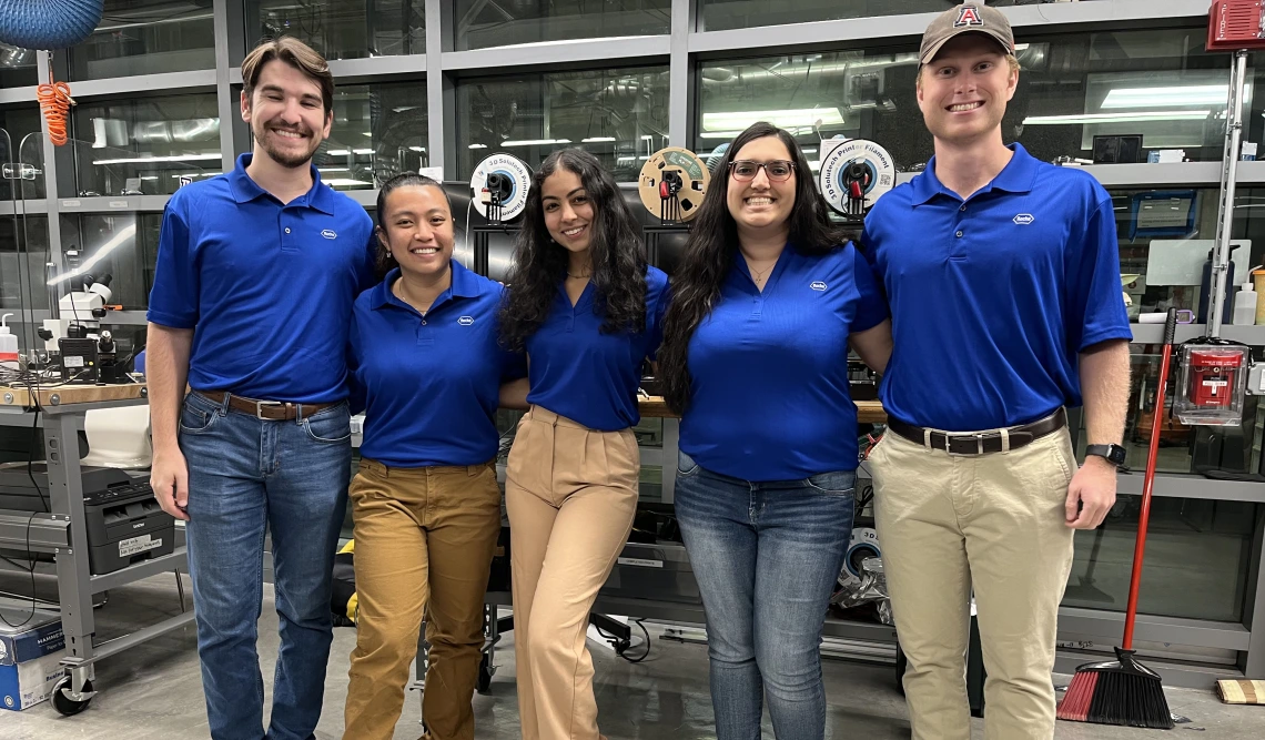 Five students stand in an engineering lab