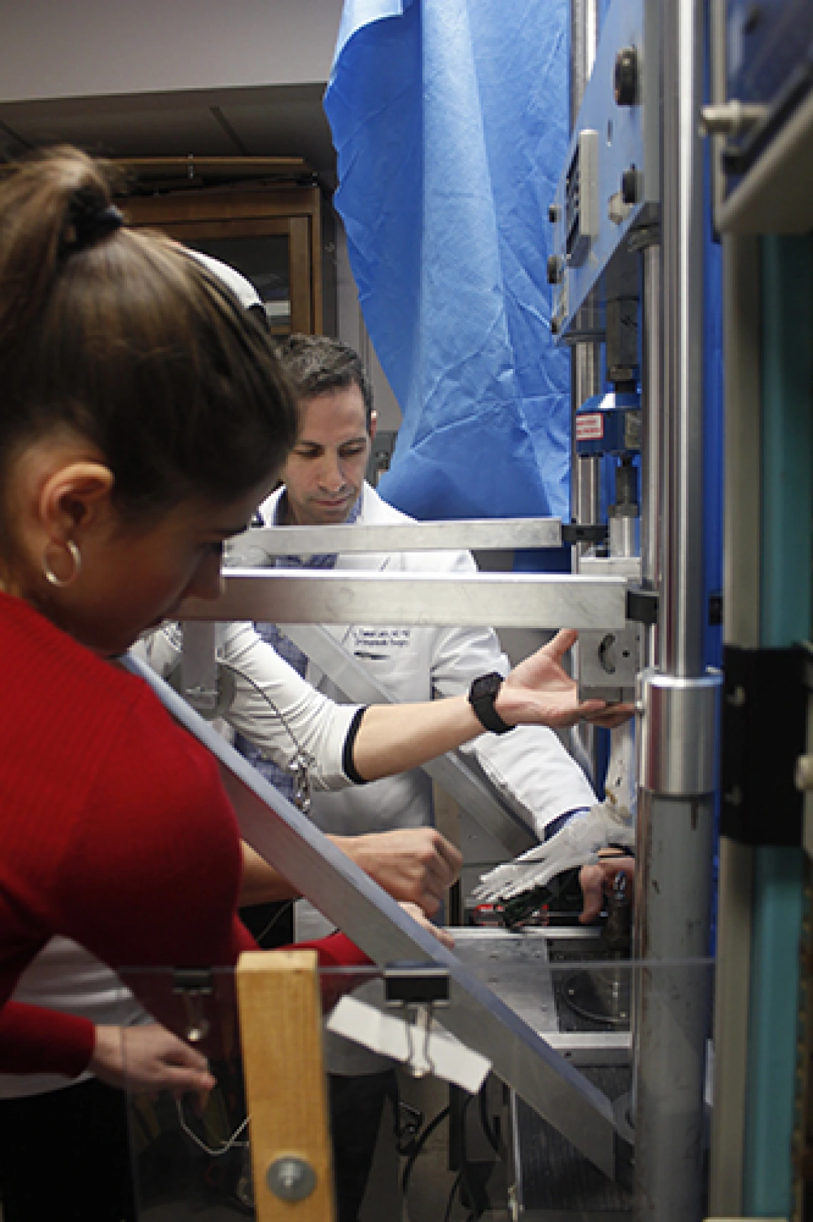 A man and a woman adjusting a replica of a skeletal foot inside a machine.