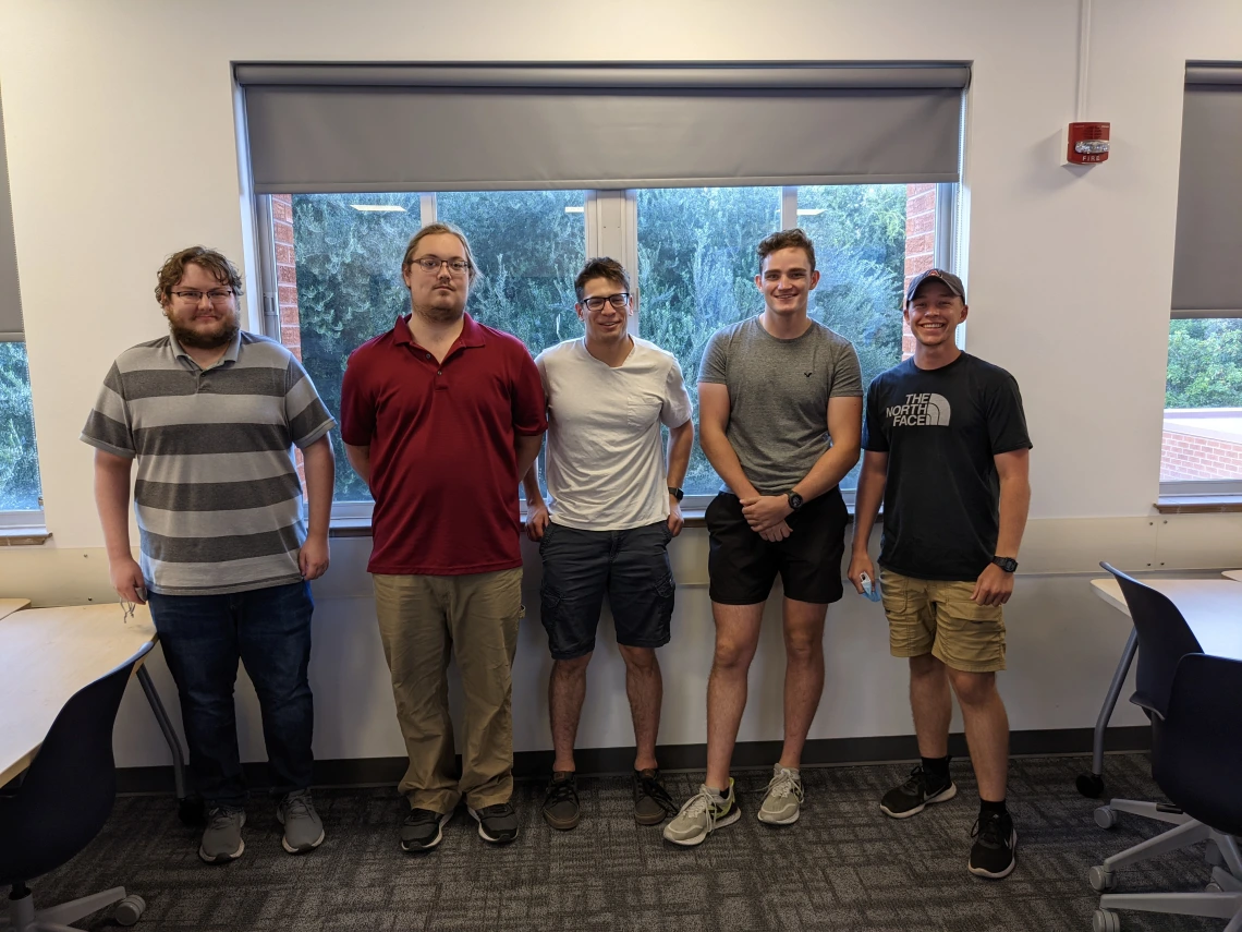 Will Mund, Quintin Deaton, Evan Burrous, Stephen Ponder and Michael Gaines stand in a row in a classroom.