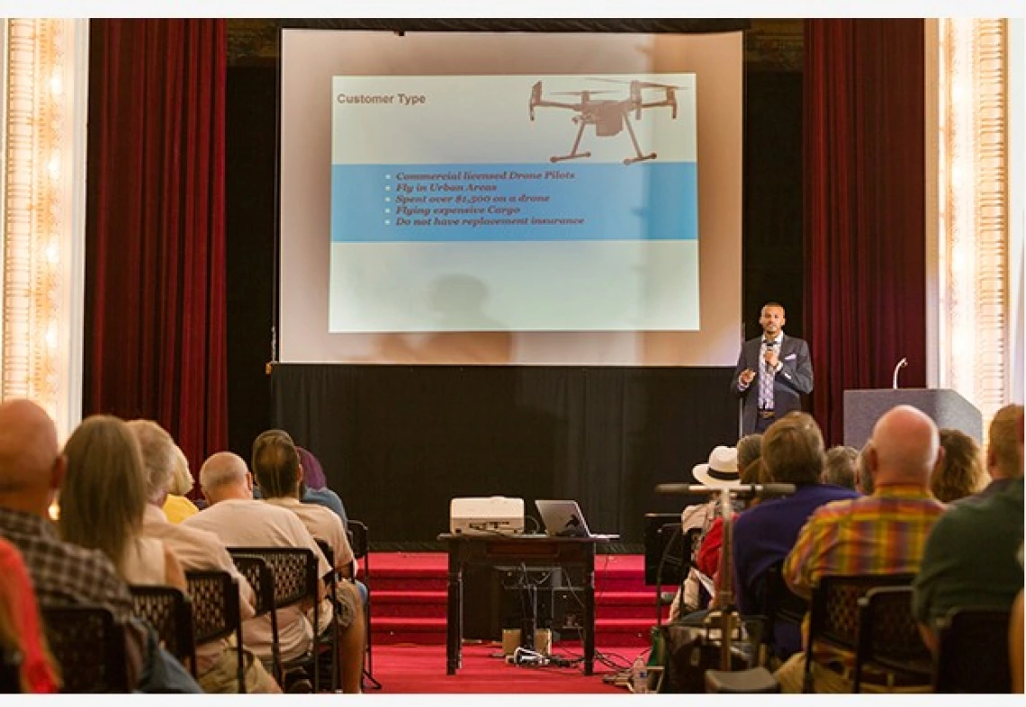 A group of people in an audience watching a presentation on drones