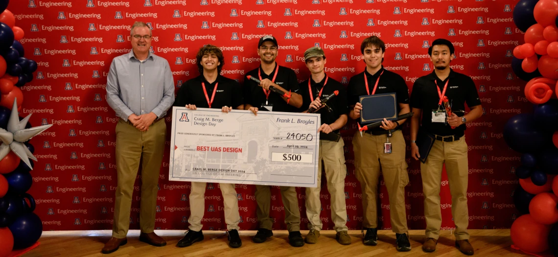 Team members hold a giant check at Design Day.