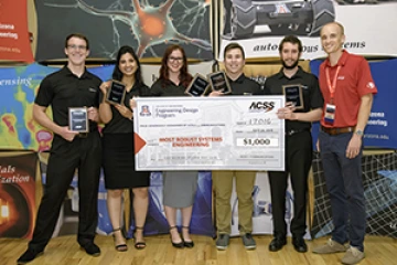 University students with presenter giving them a large award check