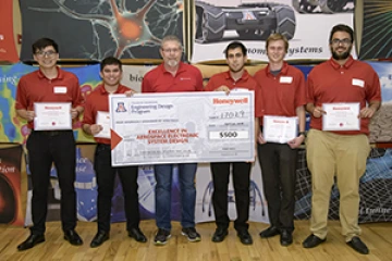 University students with presenter giving them a large award check