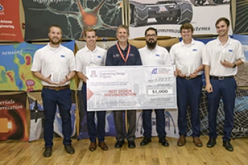 University students with presenter giving them a large award check