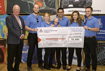 University students with presenter giving them a large award check