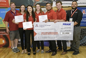 University students with presenter giving them a large award check